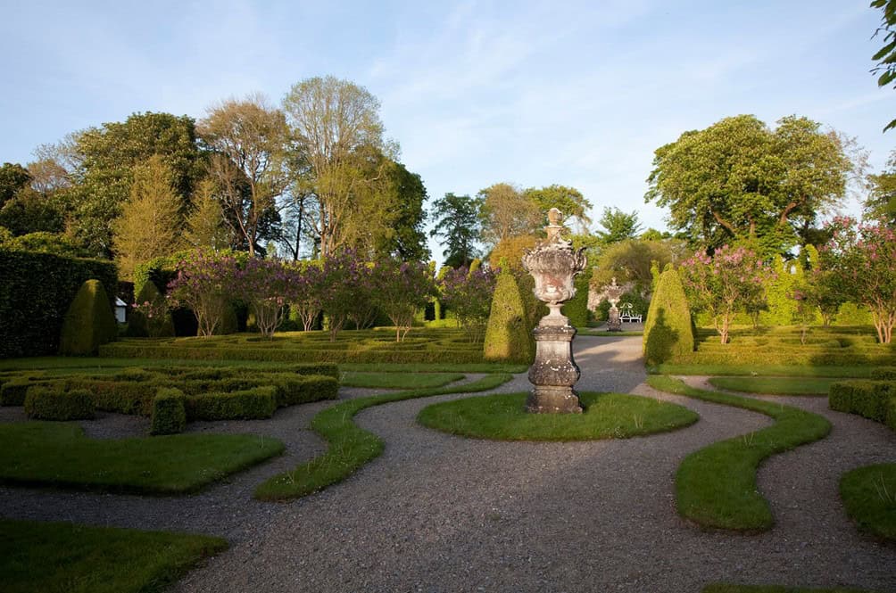 A small statue surrounded by paved paths and gardens